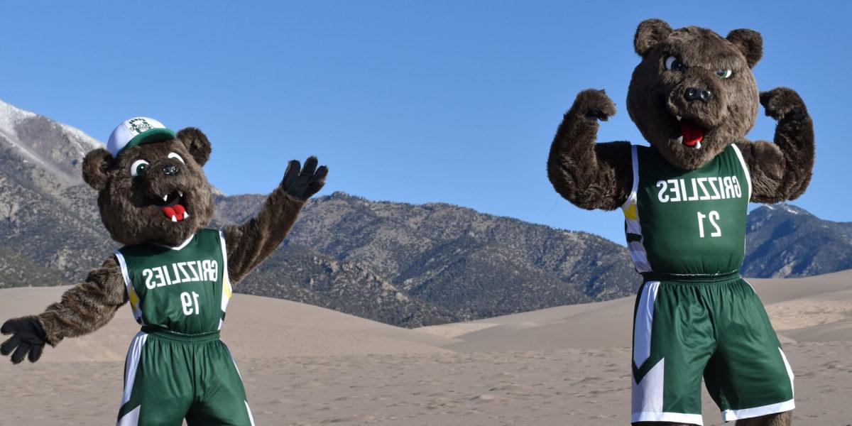 亚当斯州立灰熊队的吉祥物鲁塞特和比利在大沙丘上做手势.